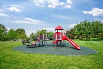 A playground with a red slide and a red and white structure.